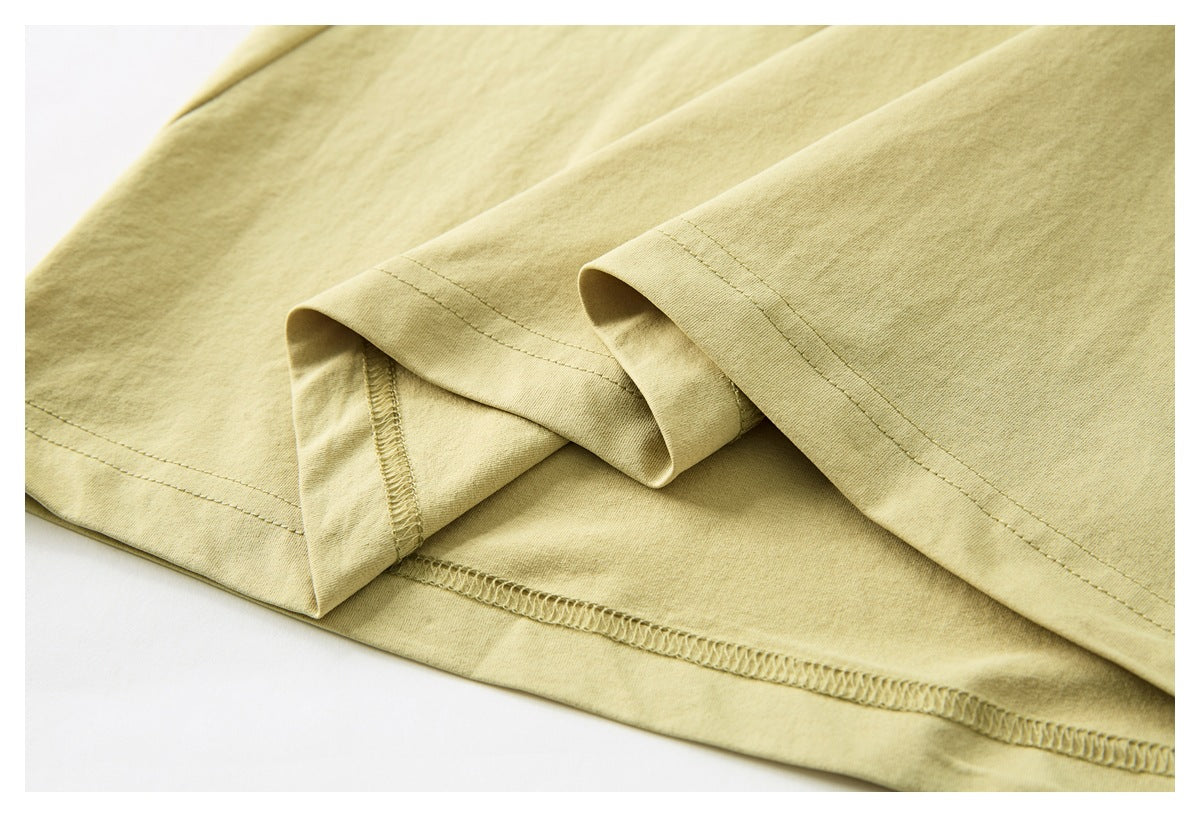 Close-up of the pale yellow T-shirt's stitched lower hem and seam finishing.