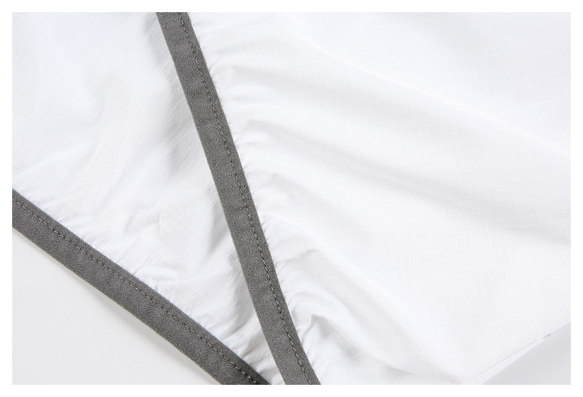 Close-up of white fabric with intersecting dark gray bound seams.