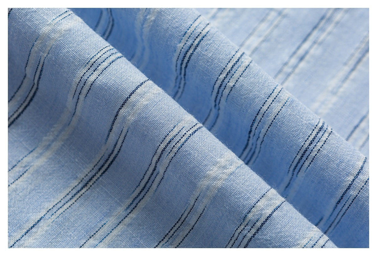 Close-up of folded light blue fabric with narrow dark blue stripes.