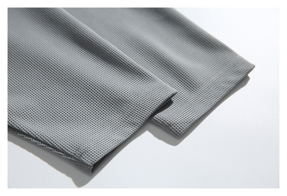 Close-up of two overlapping edges of gray grid-textured fabric on a white surface.