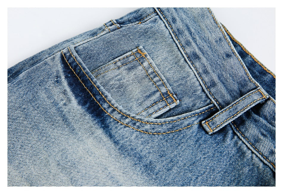 Close-up of faded blue jeans showing a small front pocket, curved pocket seam, and belt loop.