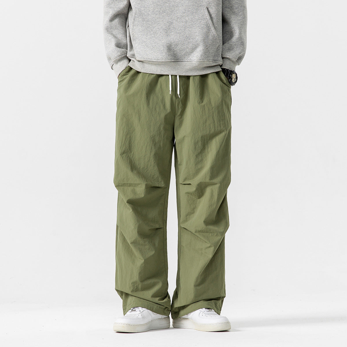 Model wearing loose olive-green drawstring pants with a relaxed fit and wide legs.