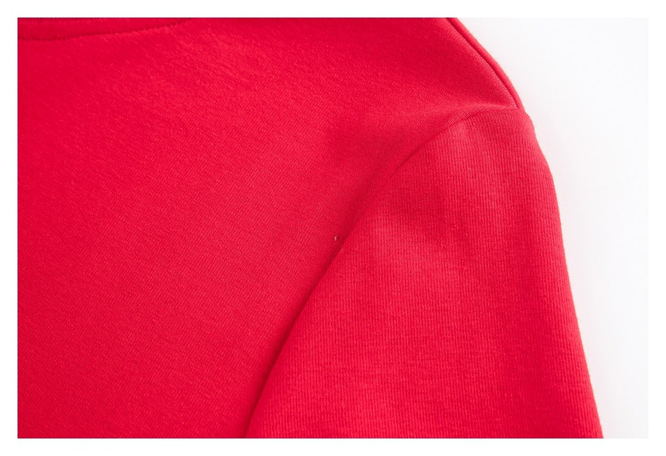 Close-up of a red garment's shoulder seam and sleeve against a white background.