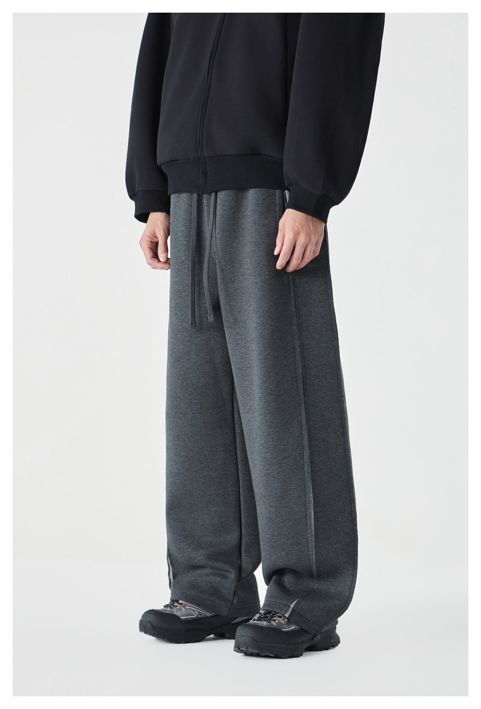 Three-quarter front view of a model wearing charcoal wide-leg sweatpants with a drawstring waist.