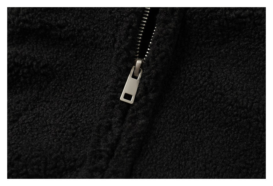 Close-up of a silver zipper pull against the black textured jacket fabric.