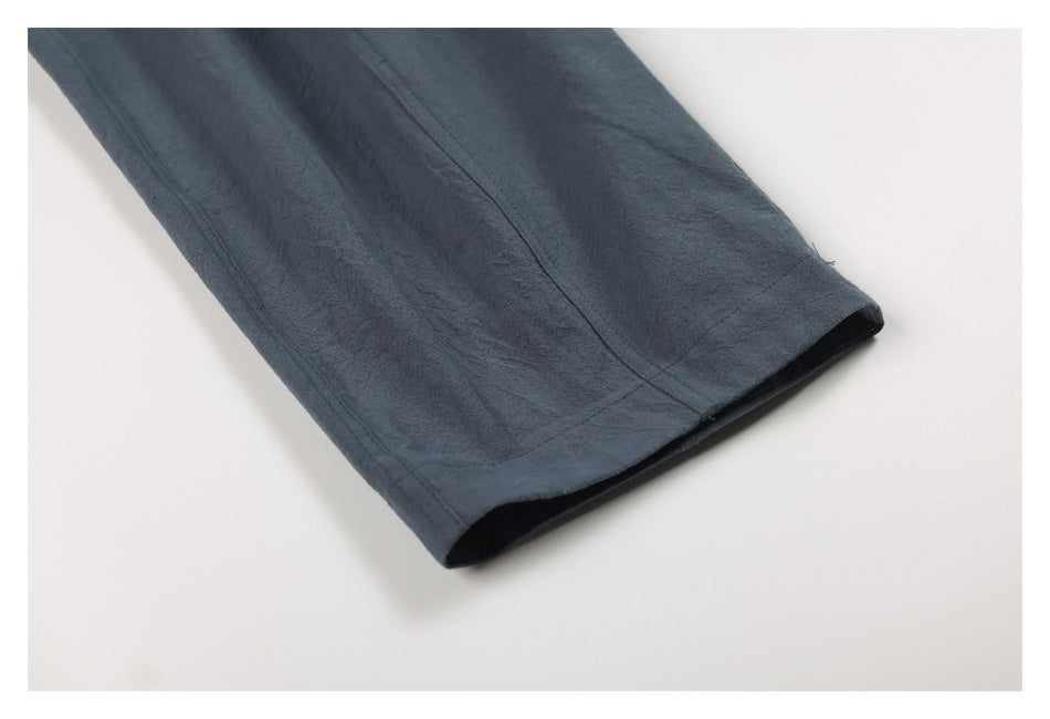 Close-up of a blue-gray trouser leg and stitched hem laid flat.