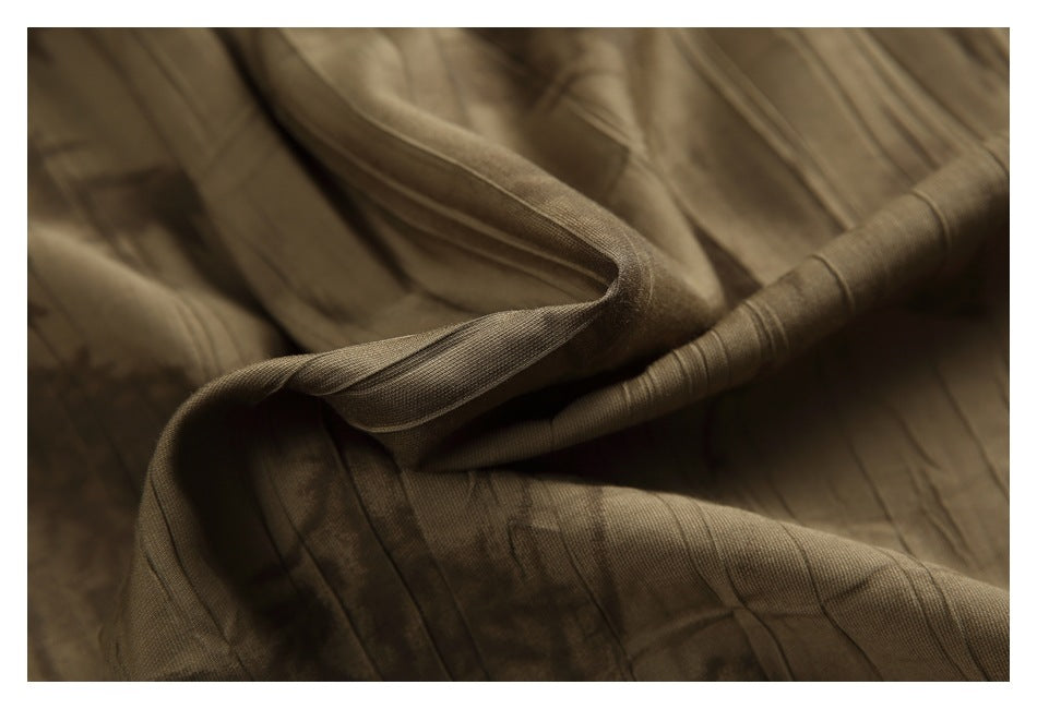 Close-up of brown-olive fabric with narrow stitched lines and folded edges.