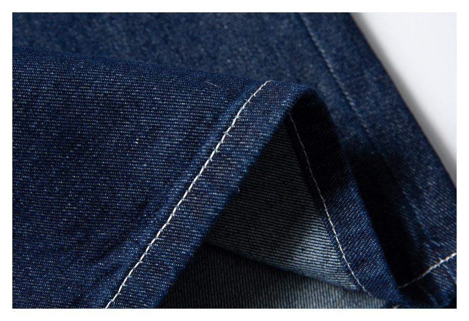 Extreme close-up of dark indigo denim shorts fabric and a folded, white-stitched hem.