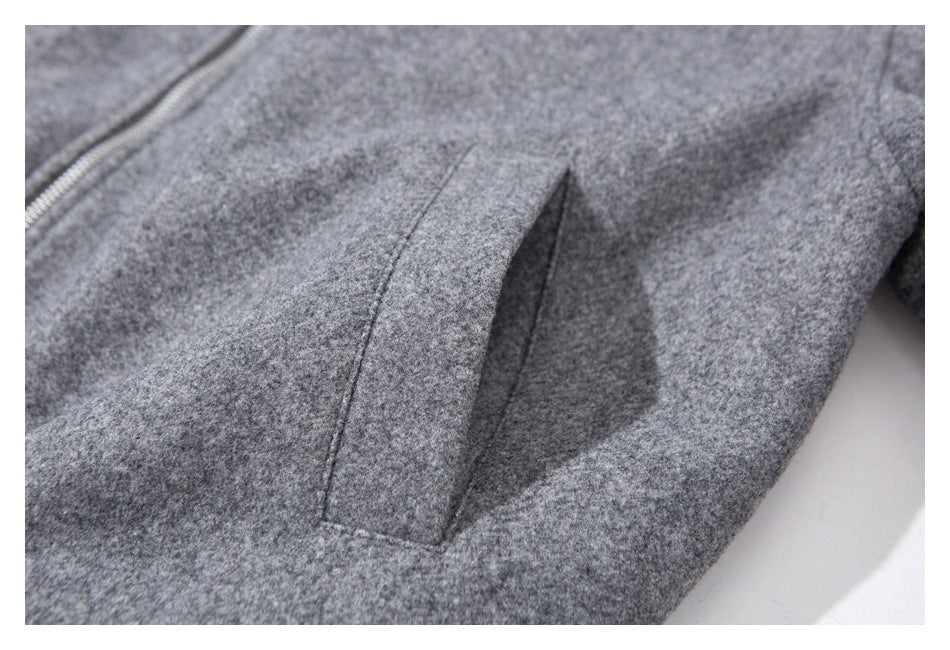 Close-up of a gray jacket's angled welt pocket and nearby zipper.