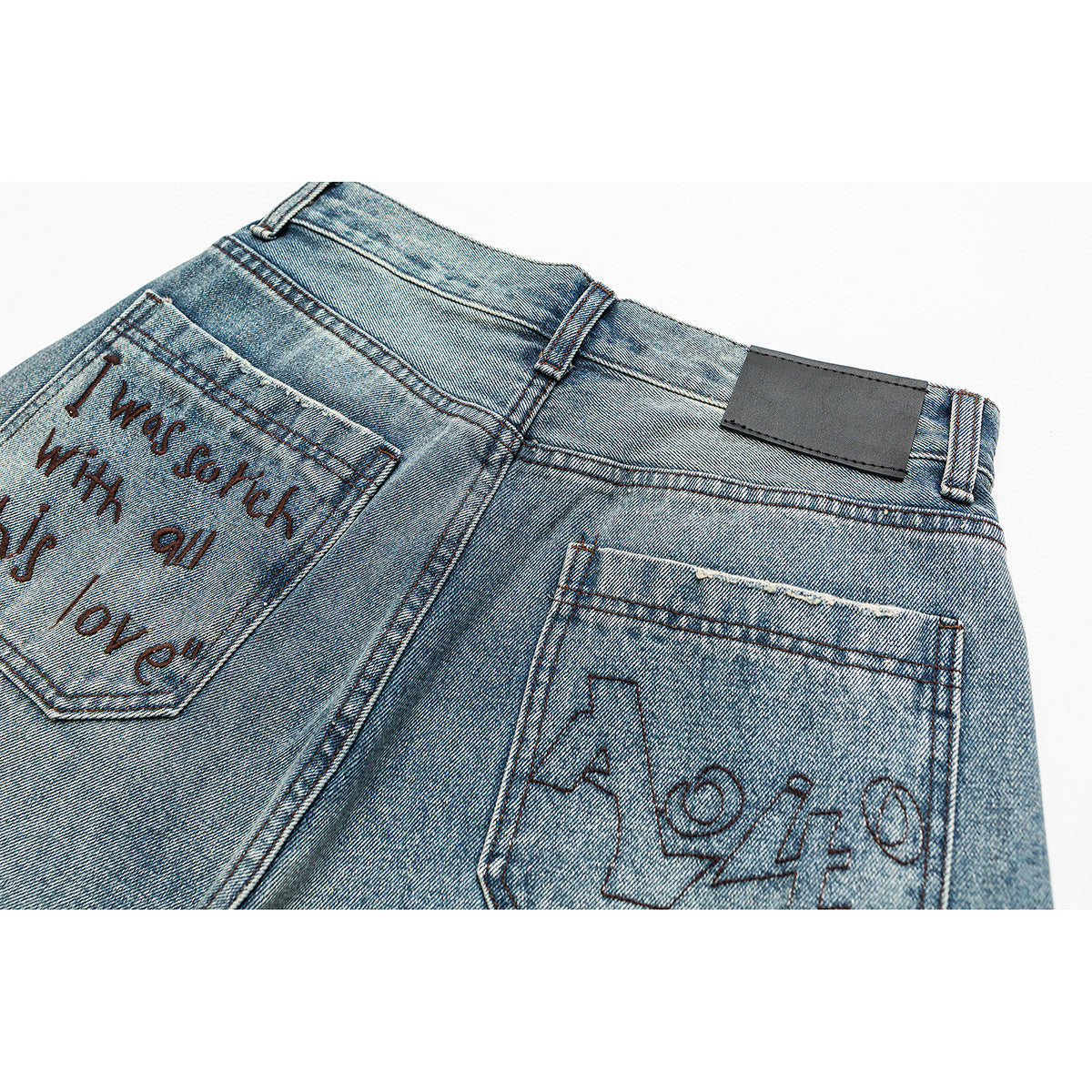 Close-up of the back of faded blue jeans with embroidered lettering on the pockets and a blank dark waistband patch.