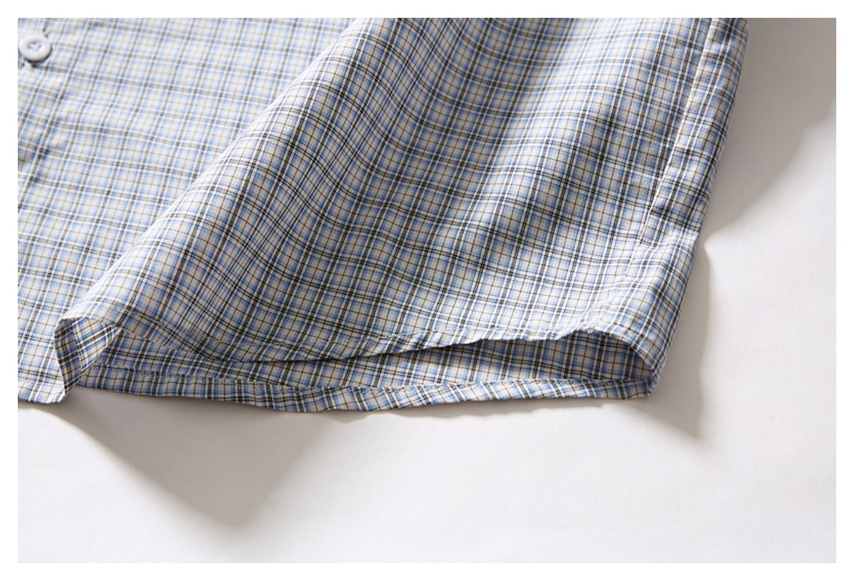 Close-up of the side hem of a white shirt with a blue and gray plaid pattern.