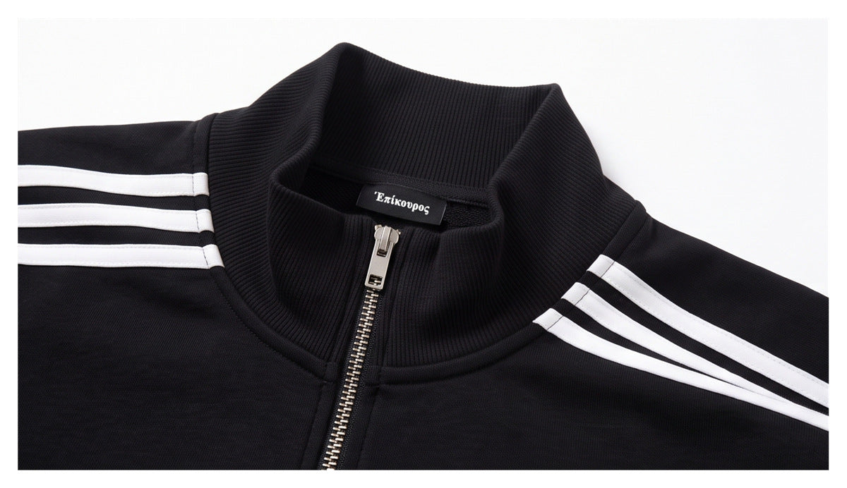 Close-up of a black track jacket's ribbed stand collar, metal zipper, and three white shoulder stripes.