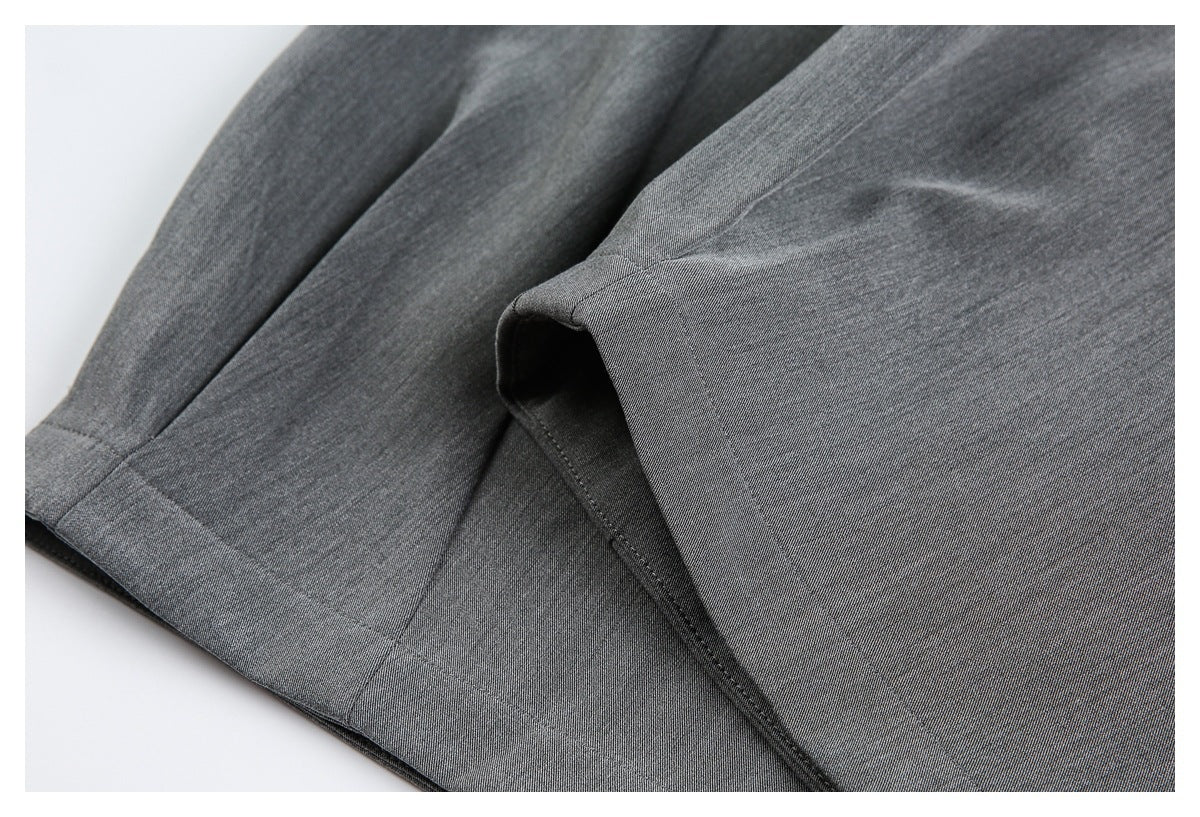 Close-up of charcoal-gray trousers showing a folded edge and stitched seams.