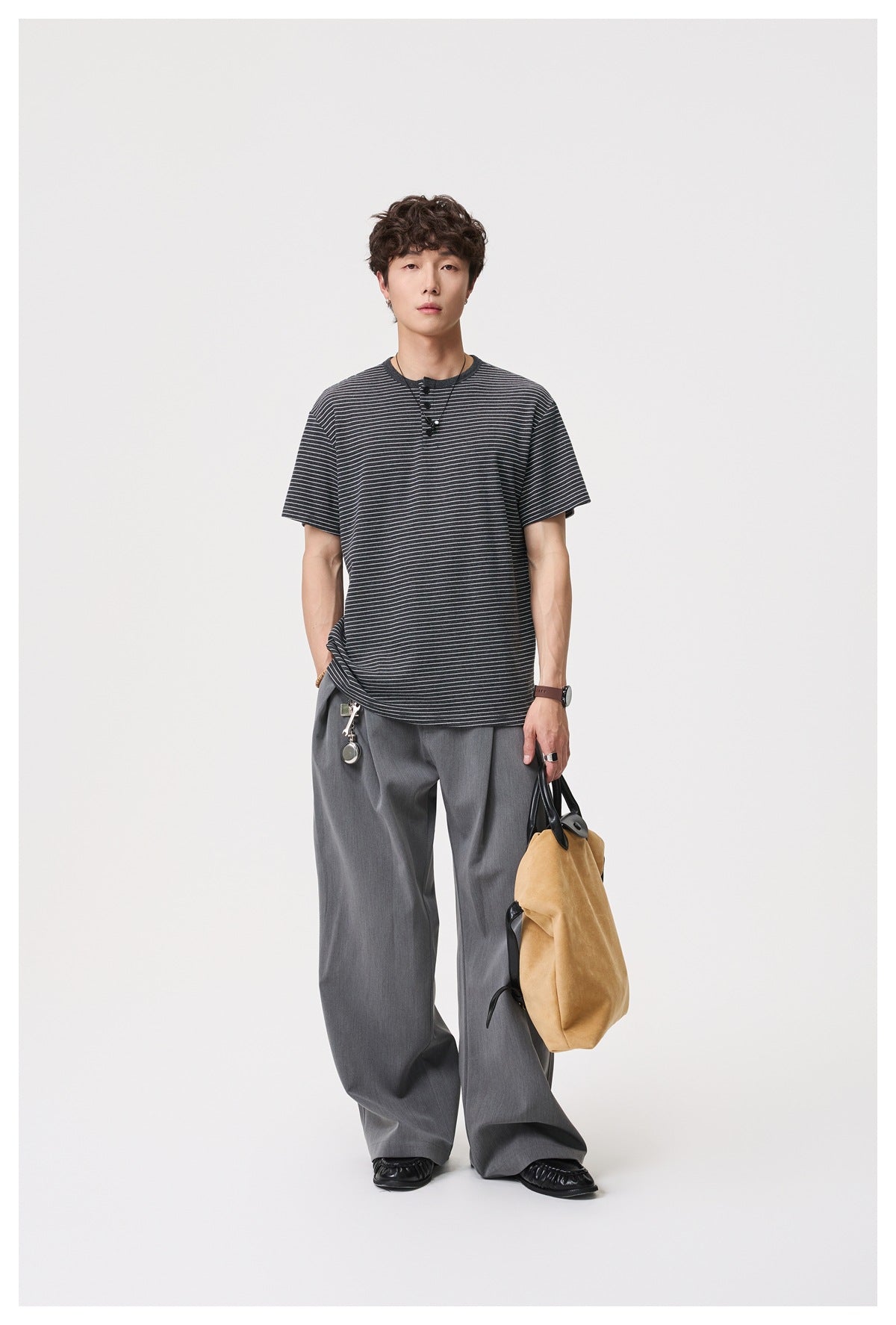 Full-length model wearing a charcoal short-sleeve T-shirt with fine white stripes and gray wide-leg trousers.