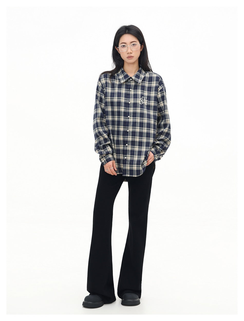 Full-length model wearing a navy and cream plaid button-up shirt with black flared pants and dark shoes.