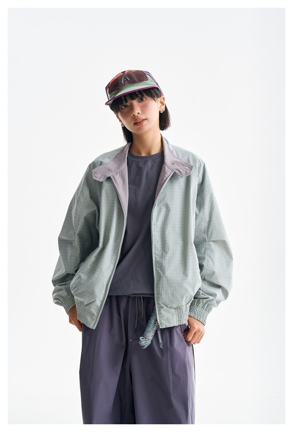 Closer front view of a model wearing a pale green checked jacket with lavender collar panels over a dark shirt.
