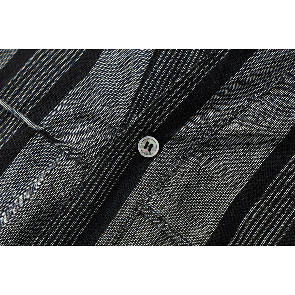 Close-up of black and gray striped shirt fabric, stitching, and a light-colored button.