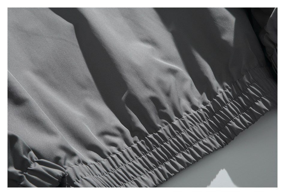 Close-up of charcoal-gray garment fabric gathered along a wide elasticized edge.