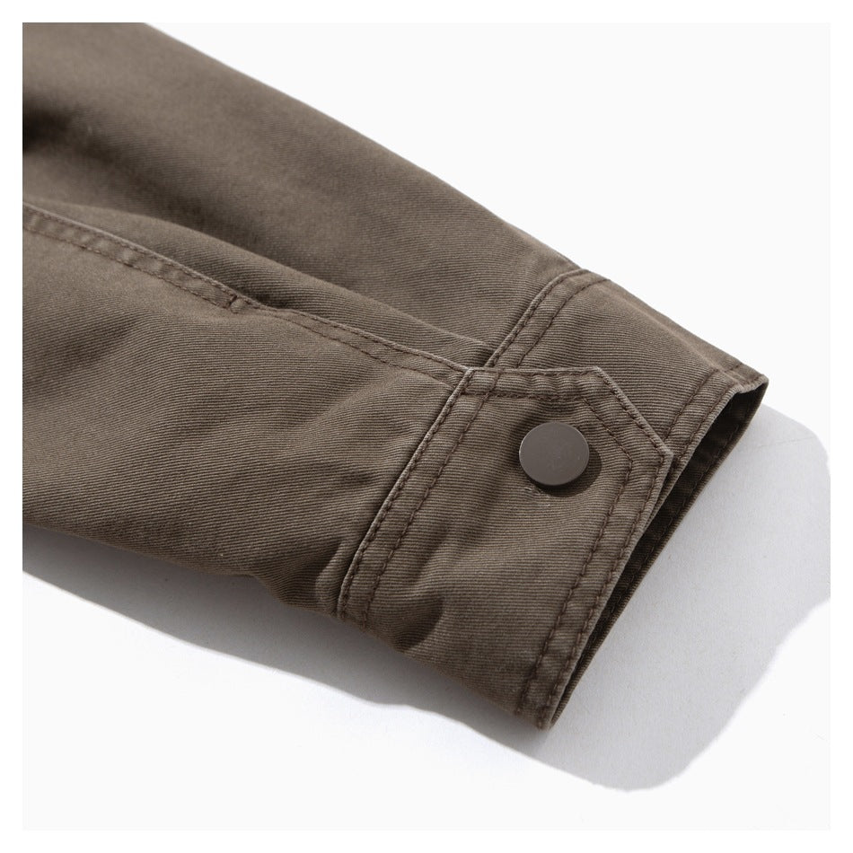 Close-up of a brown jacket sleeve cuff with a dark snap button and stitched seams.