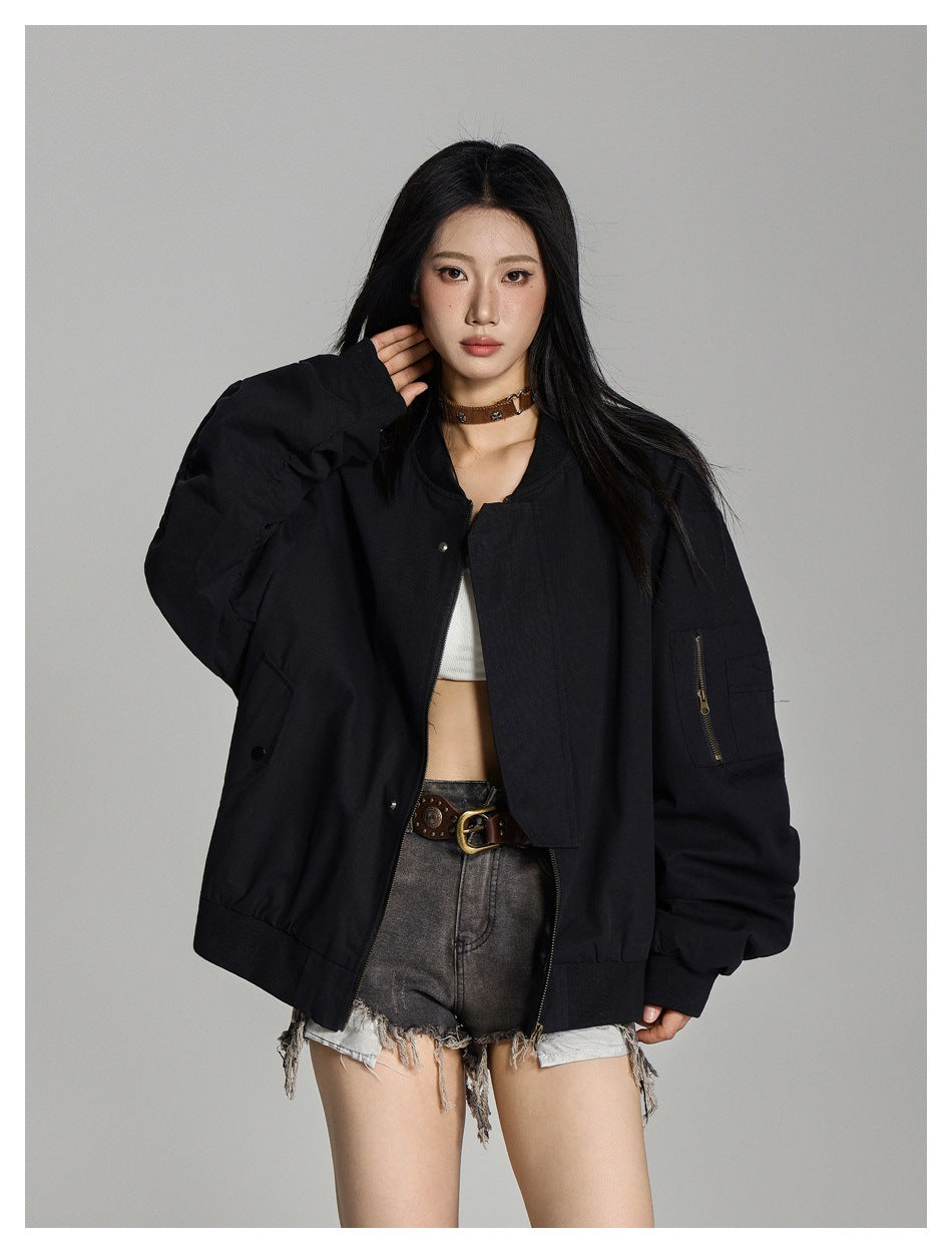 Model in a black oversized bomber jacket worn open, showing the front zipper, snap pockets, and sleeve pocket.