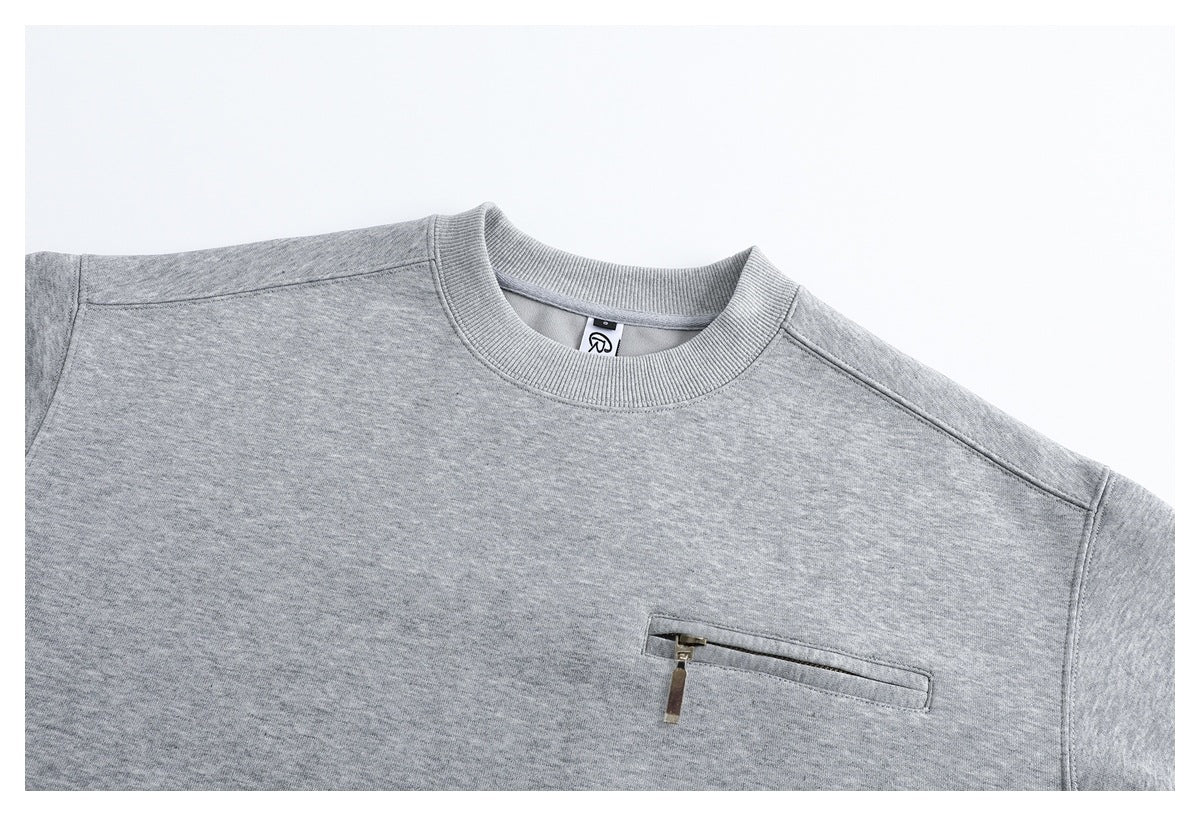 Close-up of a heather gray crewneck sweatshirt showing its ribbed collar and horizontal zip chest pocket.