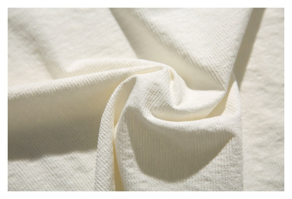 Close-up of off-white textured fabric draped into soft folds.