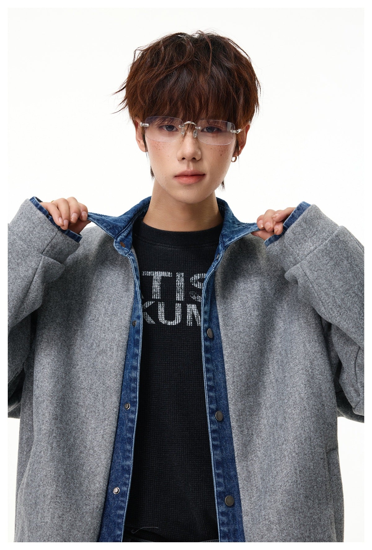 Close-up of model holding the denim collar of the gray snap-front jacket, showing blue placket and snaps