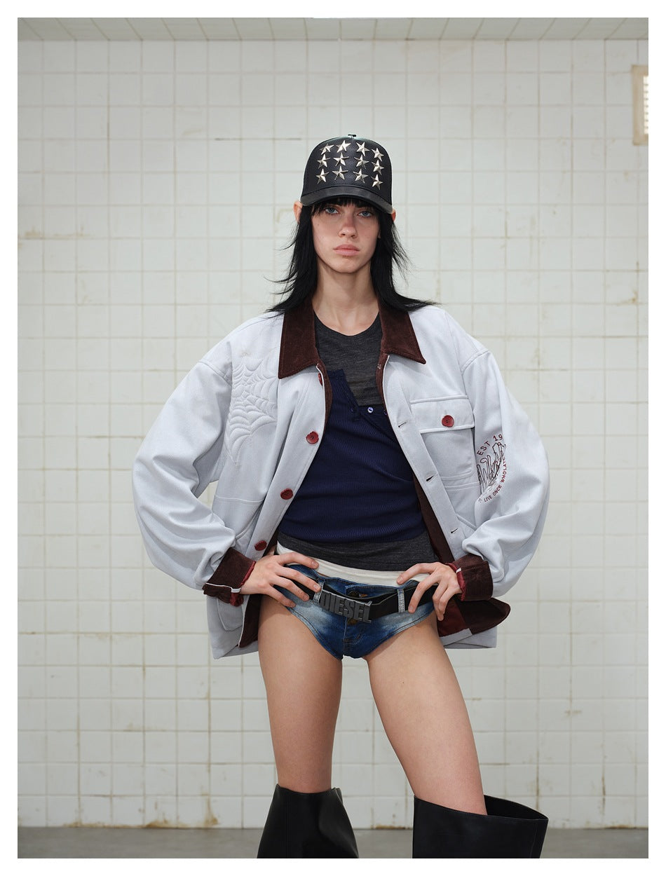 Model wearing an open light gray jacket with a dark brown collar, red-brown buttons, flap pockets, and quilted shoulder