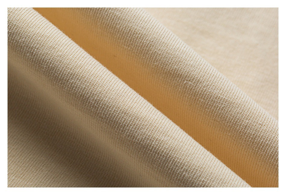 Macro view of cream knit fabric draped in folds, showing its fine ribbed texture.
