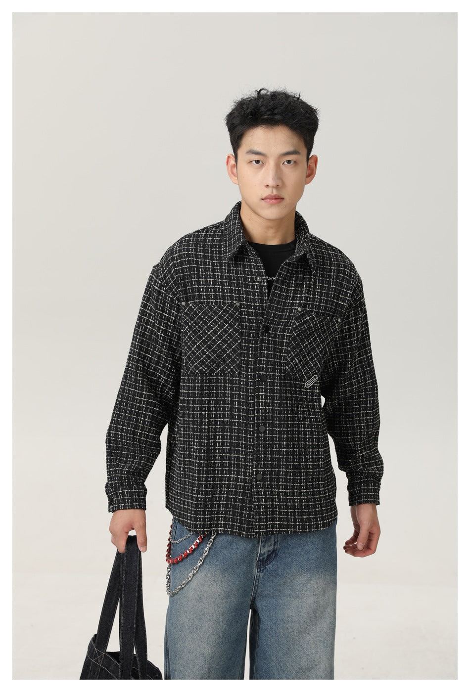 Front view of a model wearing a black-and-white grid overshirt with two chest pockets and a snap-button front.
