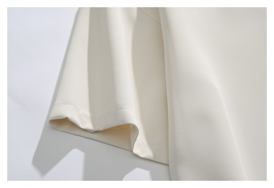 Close-up of the ivory shirt's sleeve hem and smooth fabric against a light background.