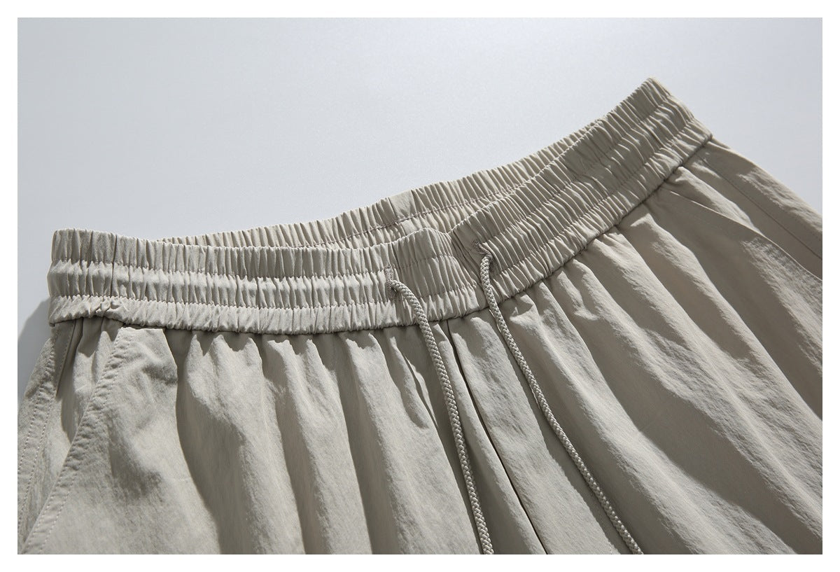 Close-up of light beige shorts showing the gathered elastic waistband and braided drawstrings.