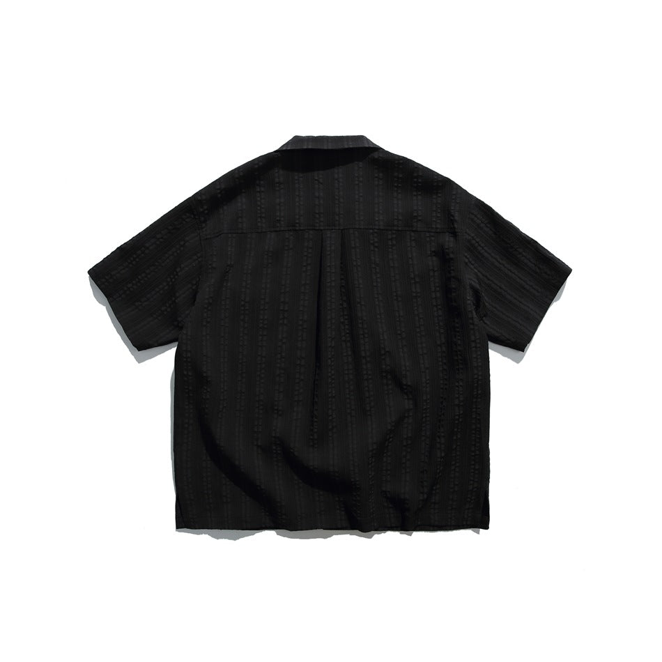 Back view of black short-sleeve camp-collar shirt with textured vertical stripes and a center back pleat