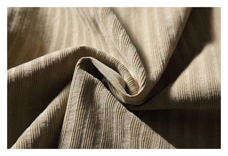 Close-up of beige fabric with narrow textured stripes and soft folds.