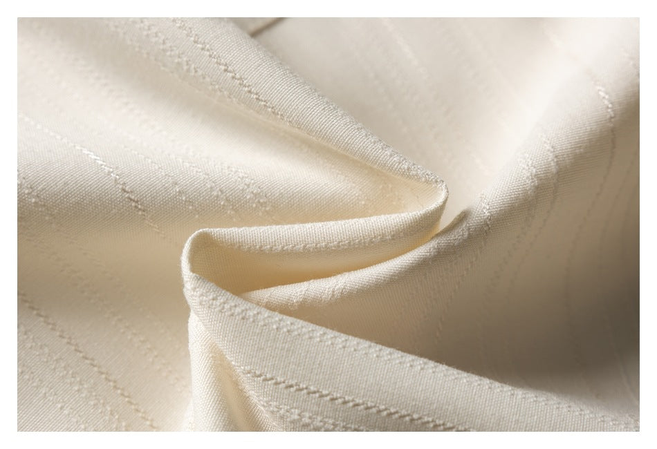 Macro view of cream fabric showing fine woven stripes and stitching.