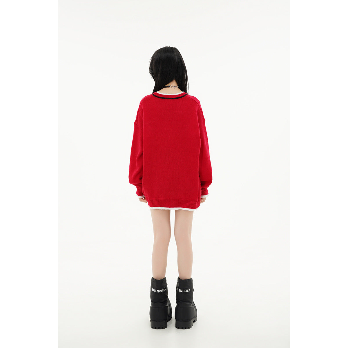 Rear view of a model wearing a red oversized cardigan with striped collar trim and a white hem edge.