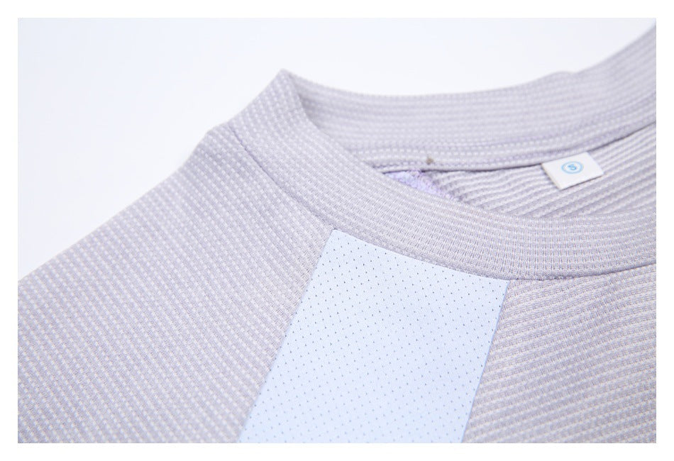 Close-up of the ribbed crew neckline and pale perforated panel on a light gray-lilac shirt.
