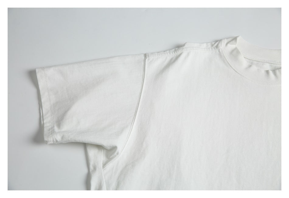 Close-up of the white T-shirt's short sleeve, shoulder, and armhole stitching.