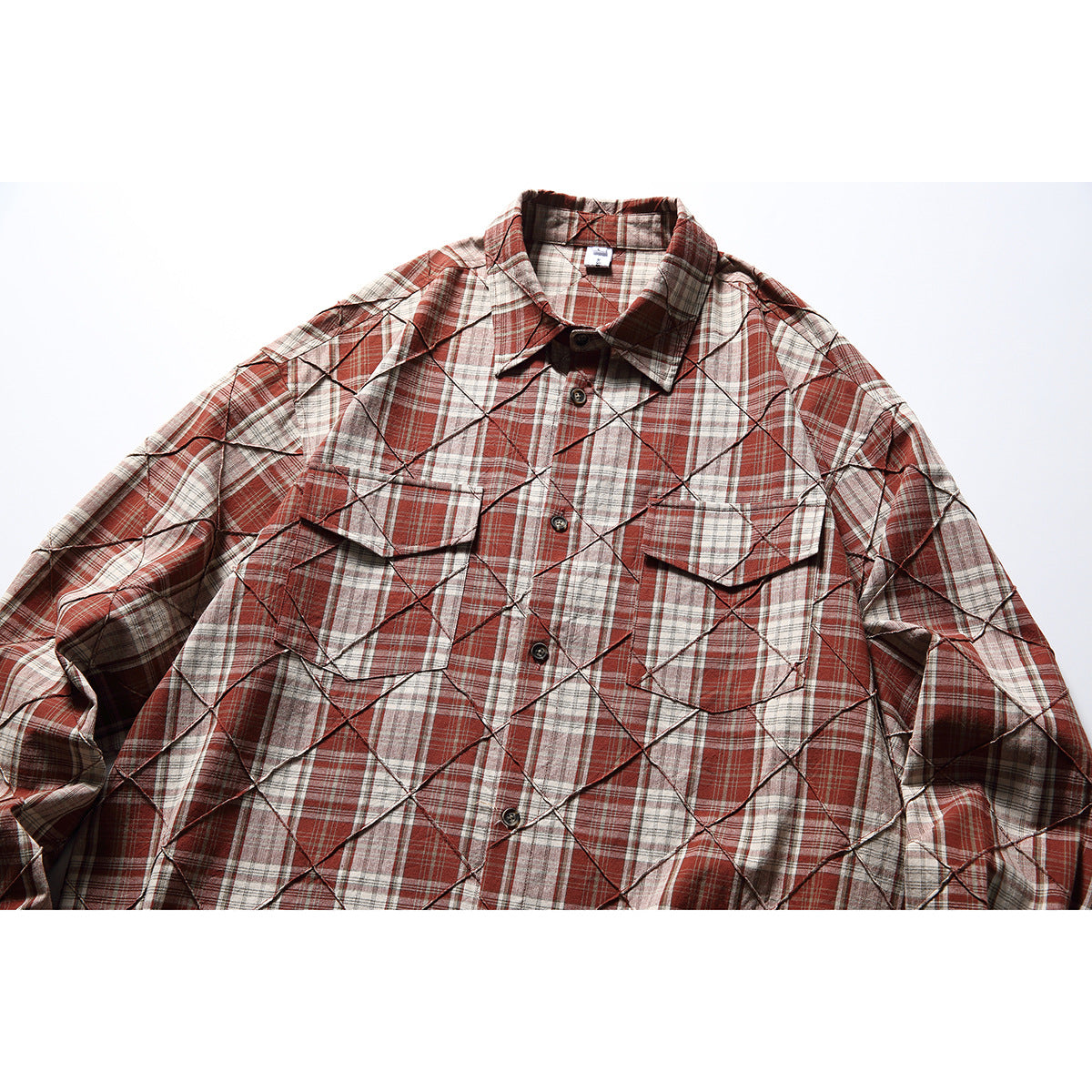Front view of a rust red, cream, and gray plaid long-sleeve shirt with diamond stitching and two flap chest pockets.
