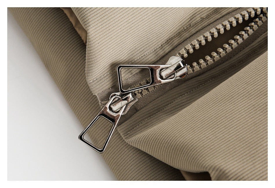 Close-up of the beige jacket's chunky zipper with two polished metal pulls.