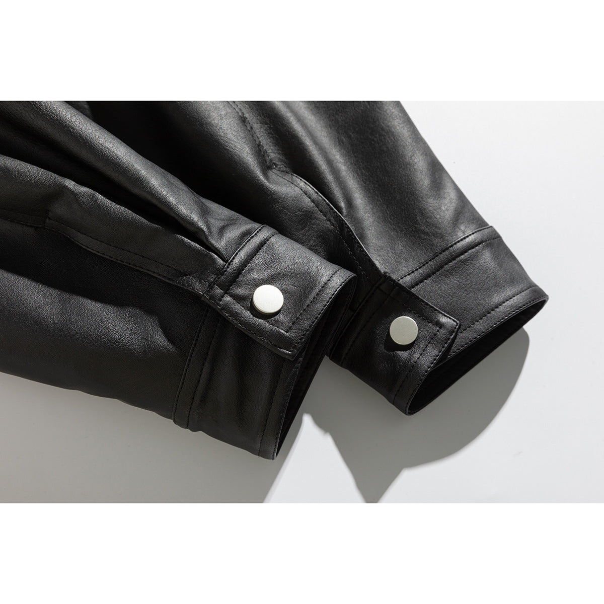 Close-up of black jacket sleeve cuffs with adjustable snap-button tabs.