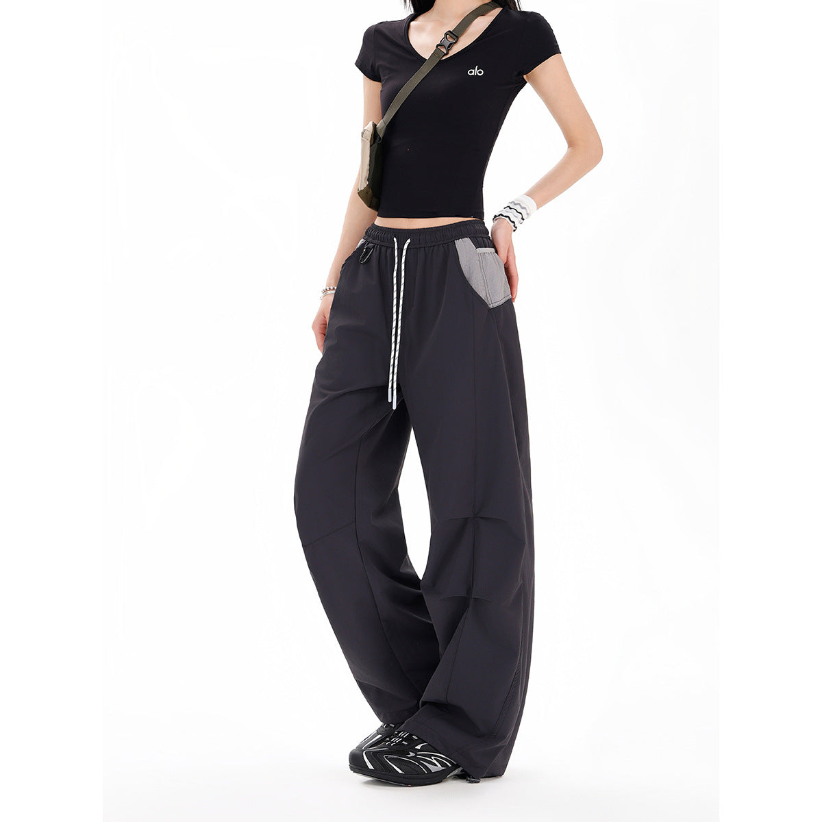 Cropped model wearing black wide-leg drawstring pants with a light gray contrast pocket and a fitted black top.
