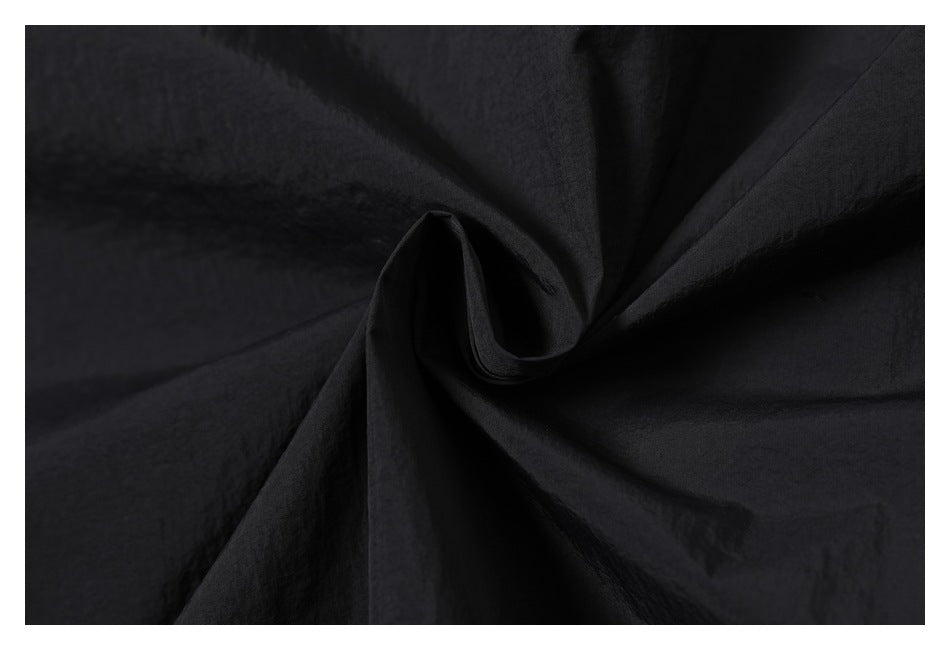 Close-up of black fabric gathered into a spiral of folds.