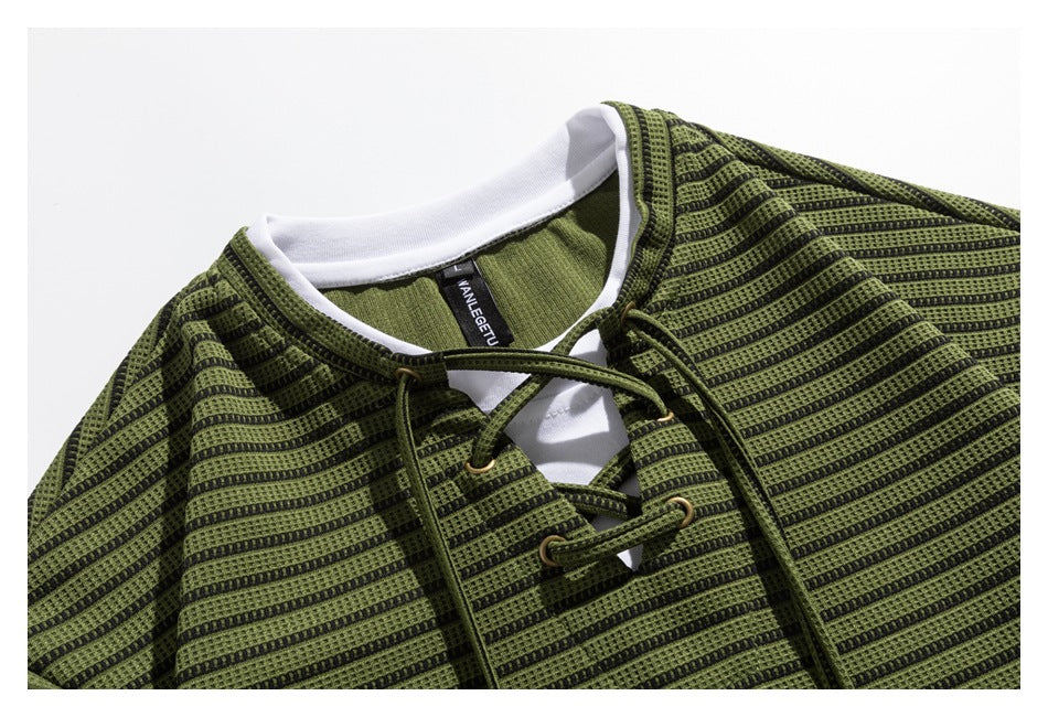 Close-up of an olive-green and black striped garment neckline with white inner trim and cord lacing.