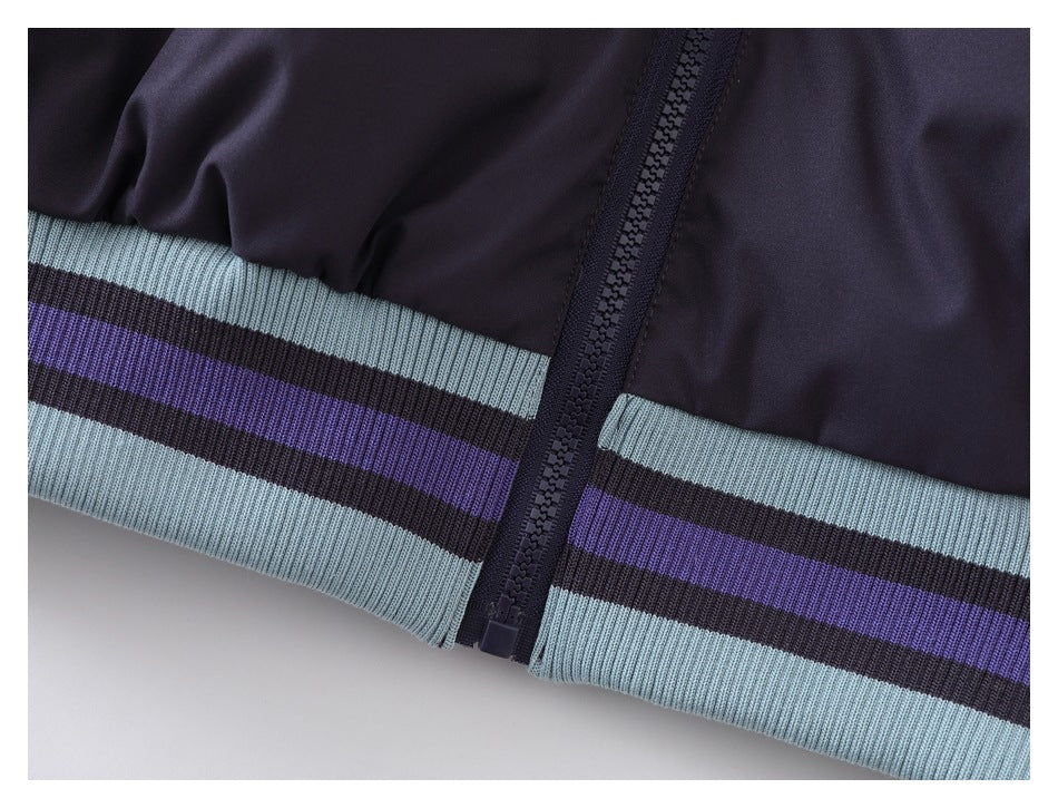 Close-up of the dark navy jacket's front zipper and striped light blue and purple ribbed hem.