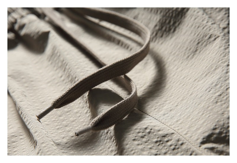 Close-up of the taupe shorts' textured drawstring with metal tips.