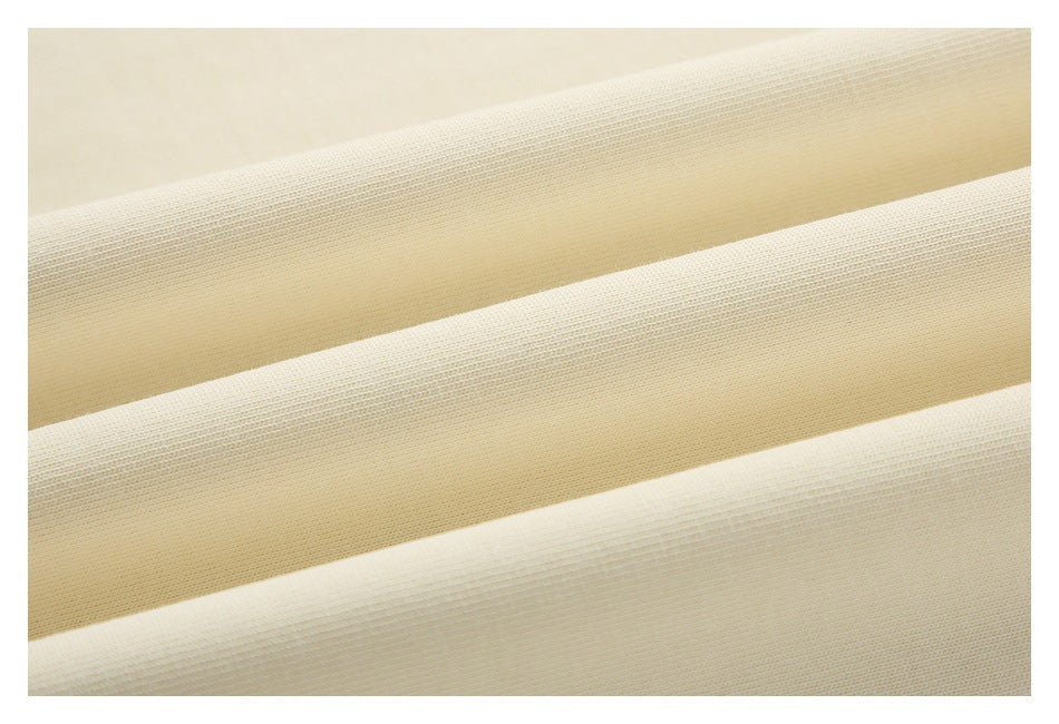 Close-up of cream fabric folded into parallel ridges, showing its surface texture.