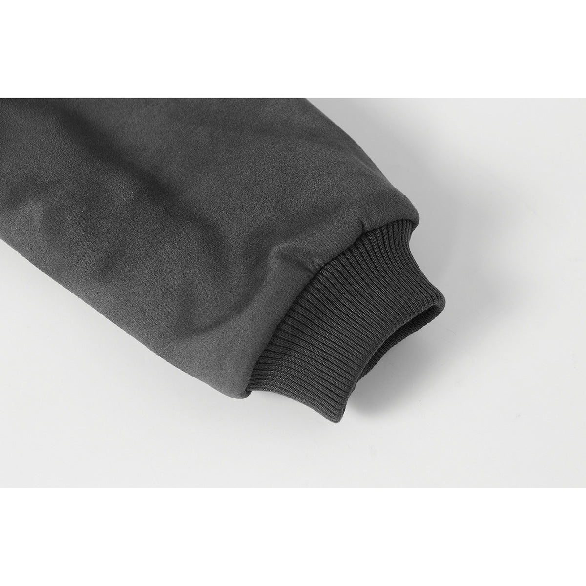 Close-up of a charcoal jacket sleeve ending in a dark rib-knit cuff.