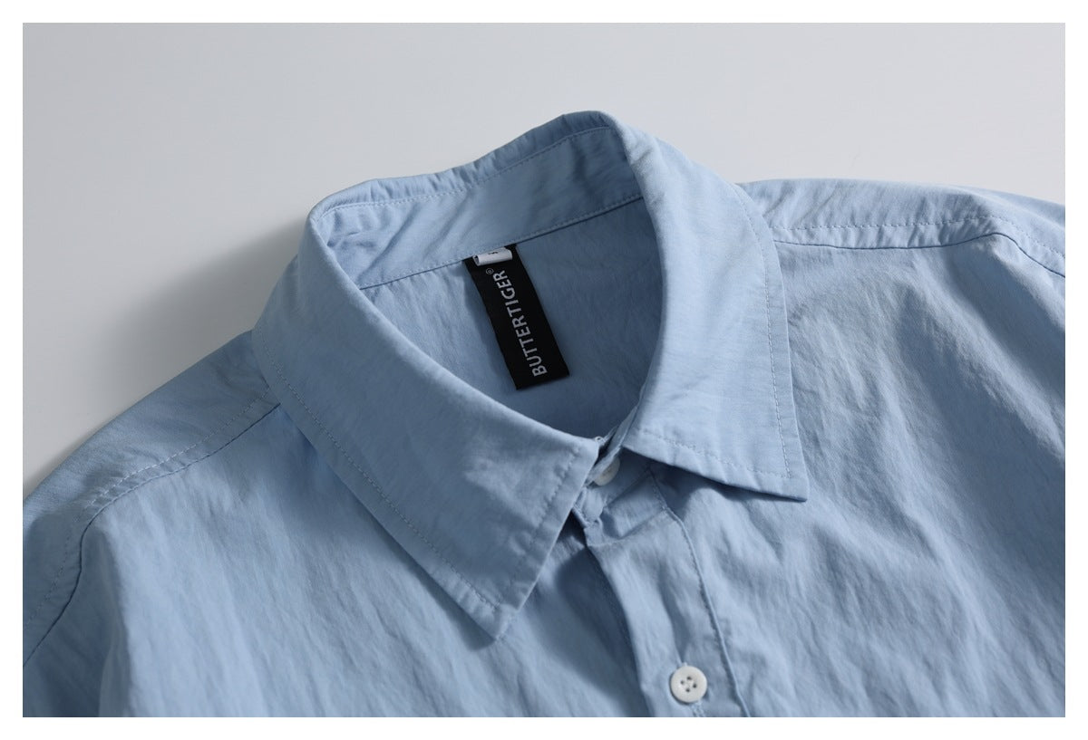 Close-up of a light blue shirt collar with a black woven neck label and white button.