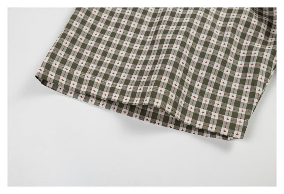 Close-up of the curved hem of a gray-green check shirt.